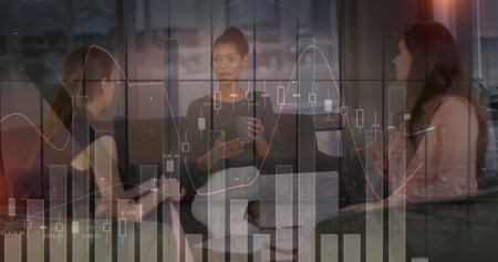 Image of data processing and diagrams over diverse female colleagues talking in office. Business, technology and digital interface concept digitally generated image.の写真素材