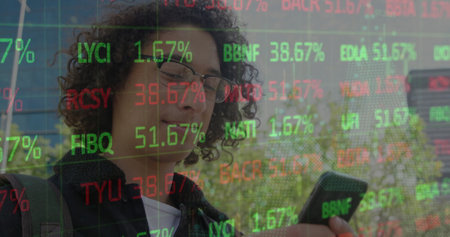 Image of young biracial man checks stock market updates on his phone. he outdoors, engaged with his...