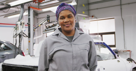 Portrait of an African American male car mechanic working in a township workshop, looking at the camera and smiling in slow motionの写真素材