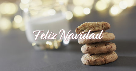 Feliz navidad text in white over christmas cookies, milk and bokeh lights. Christmas, tradition, greetings, spanish and celebration digitally generated image.の写真素材