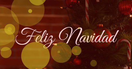 Image of yellow spots of light and feliz navidad text banner against a decorated christmas tree. Christmas festivity and celebration conceptの写真素材