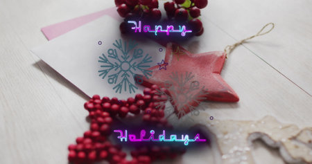 Image of happy holidays text over christmas decorations and envelopes. Christmas, tradition and celebration concept digitally generated image.の写真素材