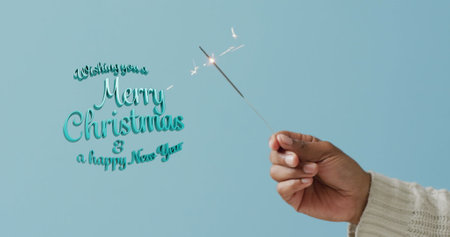 Image of christmas greetings text over man's hand holding sparkler. Christmas, festivity, tradition and celebration concept digitally generated image.の写真素材