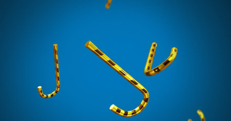 Image of christmas gold candy canes falling on blue background. Christmas, festivity, celebration and tradition concept digitally generated image.の写真素材