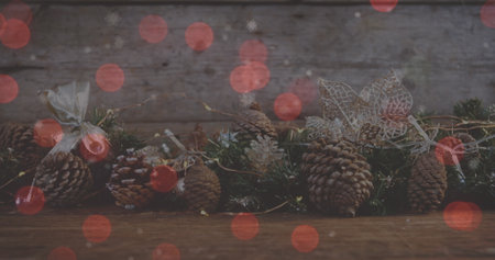 Image of red spots of light over christmas decoration with pine cones. Christmas, festivity, celebration and tradition concept digitally generated image.の写真素材