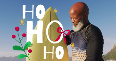 Image of christmas greetings text over african american senior man with surfboard on beach. Christmas, festivity, celebration and tradition concept digitally generated image.の写真素材