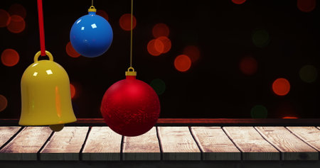 Colourful swinging christmas baubles over wood and flashing red bokeh lights on dark background. Christmas, decorations, tradition and celebration digitally generated image.の写真素材