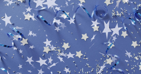 Image of stars falling over party streamers on blue background. New year's eve, christmas, festivity, celebration and tradition concept digitally generated image.の写真素材