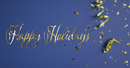 Image of happy holidays text over confetti and party streamers on blue background. New year&#39;s eve, christmas, festivity, celebration and tradition concept digitally generated image.の写真素材