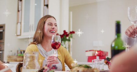 Image of snow falling over caucasian family having christmas dinner. Christmas, celebration and digital interface concept digitally generated image.の写真素材