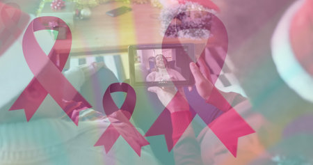 Image of pink ribbons over african american women having christmas image call. Christmas, tradition, cancer awareness and technology concept digitally generated image.の写真素材