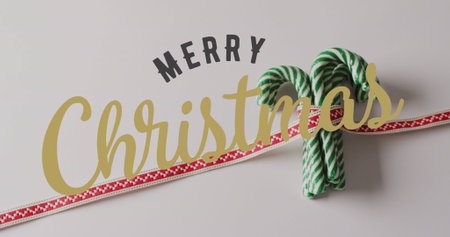 Image of christmas greetings text over christmas candy canes decorations. Christmas, festivity, celebration and tradition concept digitally generated image.の写真素材