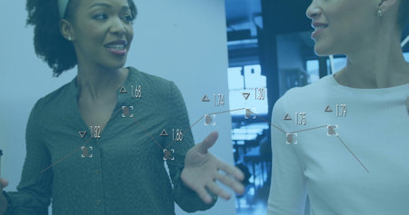 Image of data processing and diagrams over diverse female colleagues discussing work in office....