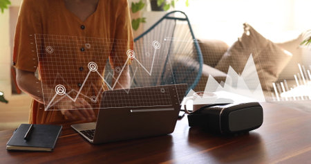 Image of financial data processing over caucasian woman using laptop. Global finance, business, connections, computing and data processing concept digitally generated image.の写真素材