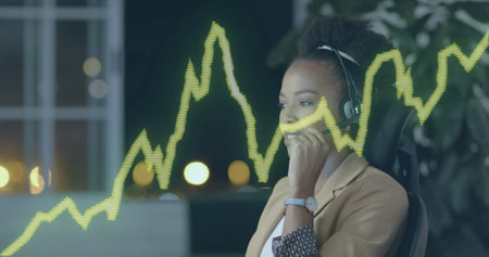 Image of financial data processing over african american businesswoman in office. Global finance, business, connections, computing and data processing concept digitally generated image.の写真素材