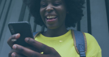 Image of icons and data processing over african american woman using smartphone. Global social media, connections, computing and data processing concept digitally generated image.の写真素材