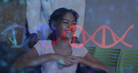 Image of dna strand over happy biracial girl in wheelchair in hospital. Medicine and digital interface concept digitally generated image.の写真素材