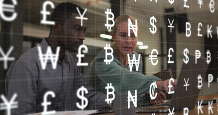 Image of currency symbols over diverse colleagues using laptop in office. Global business, finances and digital interface concept digitally generated image.の写真素材