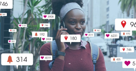 Image of social media notifications over happy african american woman talking on smartphone. Digital interface, connection, social network, lifestyle and communication, digitally generated image.の写真素材