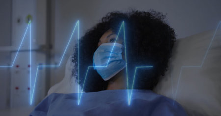 Image of cardiograph over biracial female patient in hospital bed. Technology, medicine and digital interface concept digitally generated image.の写真素材