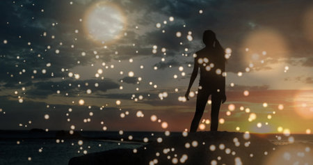 Silhouette of person dancing over glowing bokeh lights image at sunset. Dance, motion, abstract,...