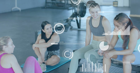 Image of diagrams and data processing over diverse women talking at gym. Technology, sport and digital interface concept digitally generated image.の写真素材
