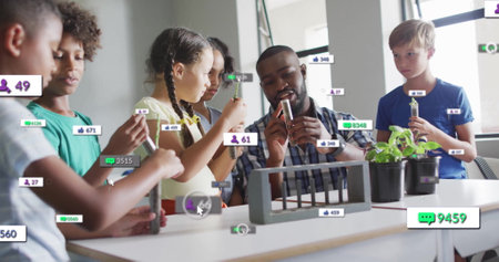 Image of media icons over diverse schoolchildren learning with male teacher. Technology, education...