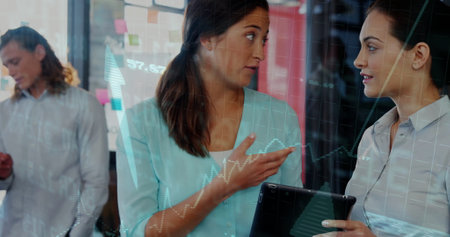 Analyzing data on tablet, women with financial graph image over office background. Business,...