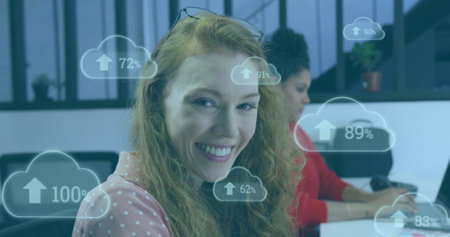 Image of cloud icons with percent growing over caucasian businesswoman in office. Global finance,...
