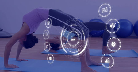 Woman practicing yoga, digital interface icons image over exercise studio. fitness, wellness,...