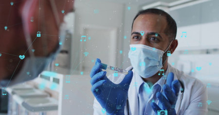 Holding vaccine vial, doctor in mask with medical icons image over scene. Healthcare, vaccination,...