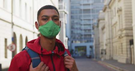 Biracial man wearing face mask in the street. backpacking holiday city travel break during...
