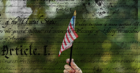 Hand holding small american flag with us constitution text overlay in background. patriotism,...