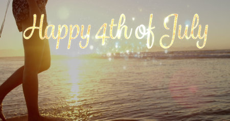 Walking on beach, person enjoying sunset with Happy 4th of July text overlay. Vacation, summer, holiday, celebration, coastline, twilightの写真素材