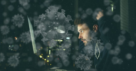 Researching coronavirus, man surrounded by digital virus illustrations on computer at home. Pandemic, healthcare, remote working, onlineの写真素材