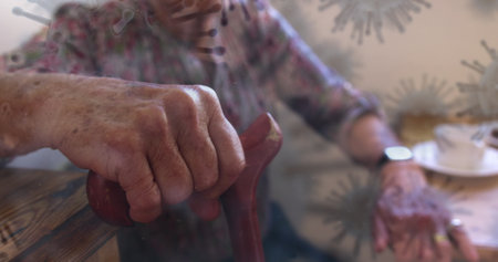 Elderly person holding cane at home, reflecting on pandemic challenges. Senior, contemplation, health, isolation, wellbeing, resilienceの写真素材