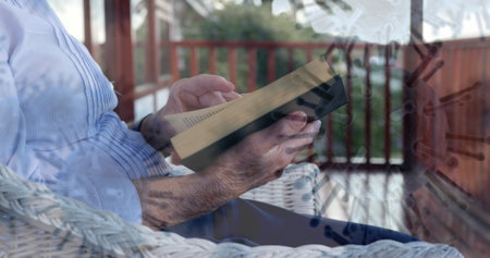 Elderly person reading book on porch, relaxing during pandemic lockdown. Relaxation, leisure,...
