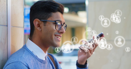 Young man using smartphone with digital icons, smiling and engaging with technology. communication,...