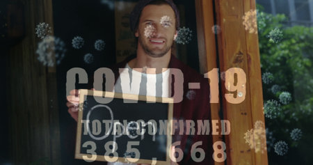 Small business owner smiling through window during pandemic. Entrepreneur, storefront, resilience, local business, reopening, optimismの写真素材