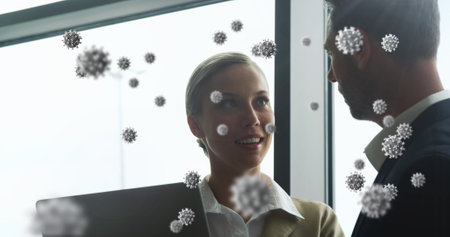 Image of floating macro cells over Caucasian woman using laptop at airport. Public transport reopening with social distancing during pandemic concept.の写真素材