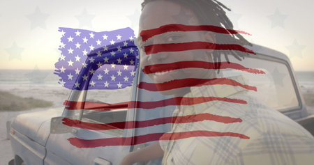 Image of american flag drawn over portrait of biracial man by a car by seaside on summer holiday. american society diversity concept digital compositionの写真素材