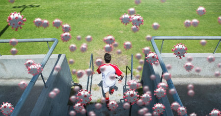 Image of 3d coronavirus cells floating over soccer player holding ball on empty stadium. Global Covid 19 coronavirus pandemic sport concept digitally generated image.の写真素材