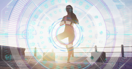 Image of statistics and graphs over woman practising yoga on promenade by the sea. Digital interface global sport and performance concept digitallygenerated image.の写真素材