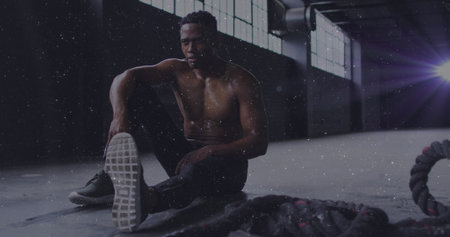 White particles against african american man taking a break from working out. sports and fitness conceptの写真素材