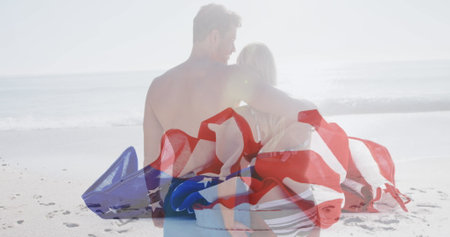American flag falling against rear view of caucasian couple hugging on the beach. american independence patriotic holiday conceptの写真素材