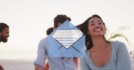 Image of email envelope digital icon over friends dancing on beach. digital interface, social media...