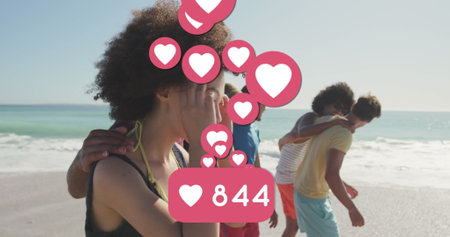 Image of numbers and love digital icons over smiling friends on beach. digital interface, social media and global networking concept digitally generated image.の写真素材