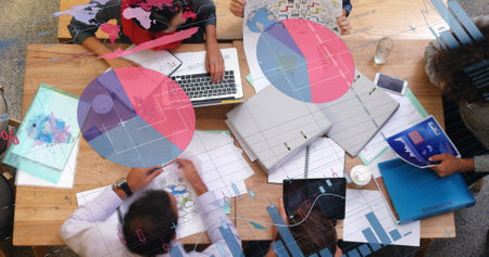 Team collaborating on project with laptops and documents at modern office desk. Collaboration,...