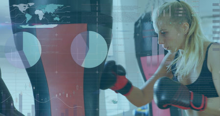 Woman training with punching bag, digital interface overlay showing data and graphs. Fitness, boxing, technology, workout, analytics, exerciseの写真素材
