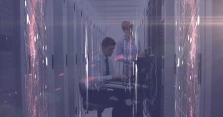Image of network of connections and glowing spot of light against two technicians working. digital...